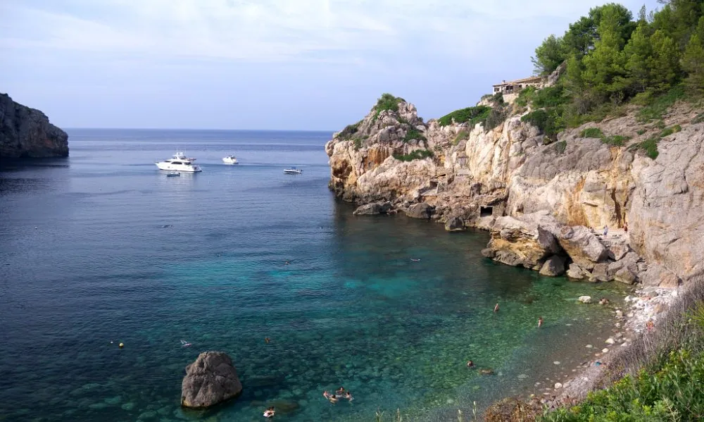 Small boats moored in the clear waters of Cala Deià