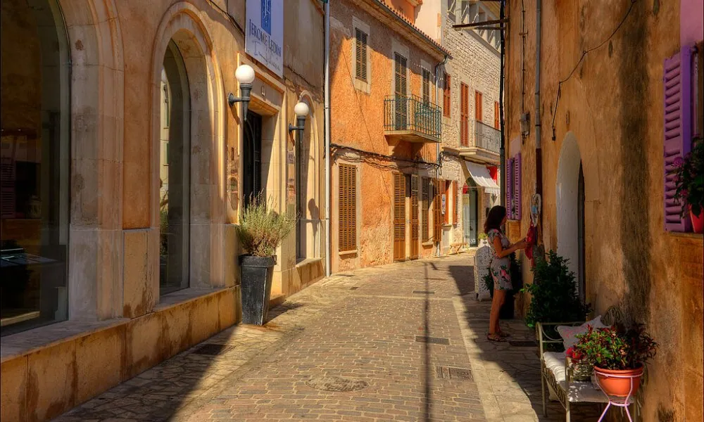 Pedestrian street lined with golden sandstone buildings in Santanyí town centre
