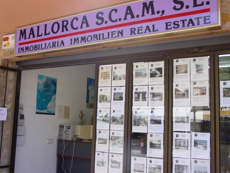 Fachada de uma agência imobiliária em Maiorca com montra repleta de anúncios de imóveis para venda.